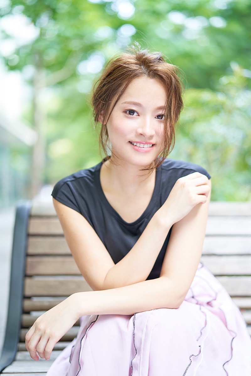 緑を背景にベンチに座る女性のポートレート